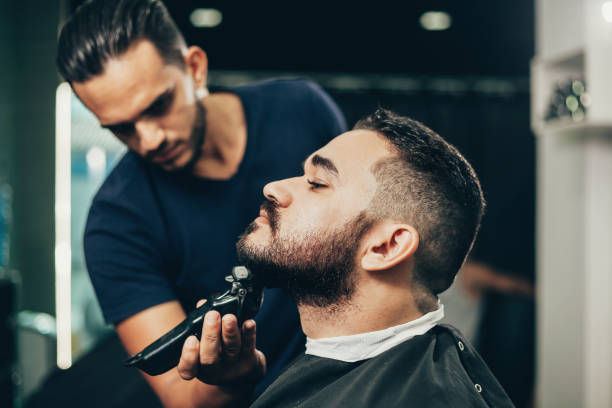 cliente durante la toelettatura di barba e capelli nel barbiere - negozio del barbiere foto e immagini stock