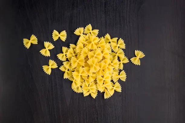A pile of farfalle pasta on dark black background