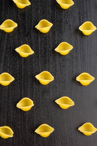 istock Pattern of A pile of conchiglie paste shells on black background 1140212799