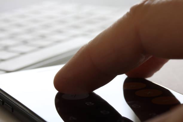 istock Smartphone with fingers touching the screen and keybord in background. Selective focus and extreme close up and hard contrast fading out for copy writing 1140219206
