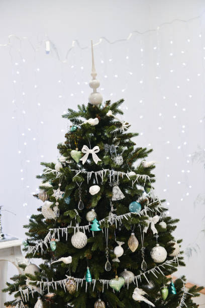 istock white winter Christmas decor for studio with a Christmas tree, in bright white shades. Christmas decorations toys, candles, fir branches 1140220988