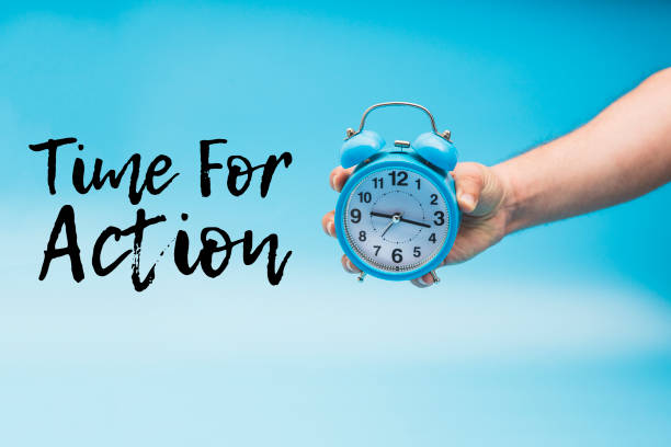 istock Time for Action and a Hand Holding a blue Analog Alarm Clock 1140230301