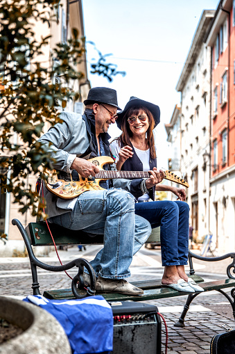 Cheerful Mature Street Performers Playing Electric Guitar and Singing on City Street.