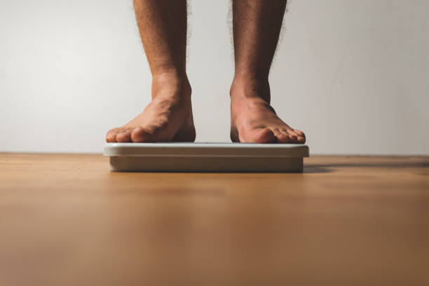 istock Weight loss and diet concept. man standing on scale. 1140234012