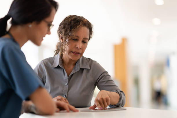 Female doctor talking with her senior patient A female doctor talks to her senior patient about her options for maximizing her health. She uses a tablet to show her the charts. medical procedure stock pictures, royalty-free photos & images