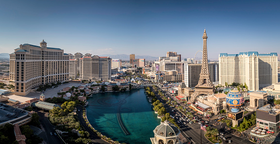 Daytime high-angle view of the Las Vegas strip featuring the Eiffel tower replica and the fountains of Bellagio as well as the resort hotels Bellagio, Paris-Las Vegas, Ballys and Caesars Palace.