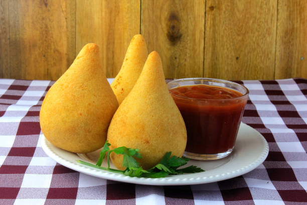 Coxinha in the dish, traditional Brazilian cuisine snacks stuffed with chicken, on rustic wooden table. Front view