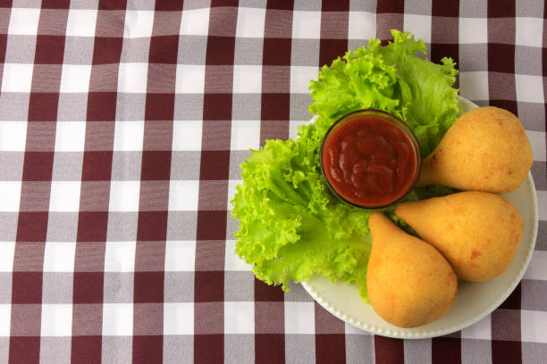 Coxinha in the dish, traditional Brazilian cuisine snacks stuffed with chicken, on rustic wooden table. Top view