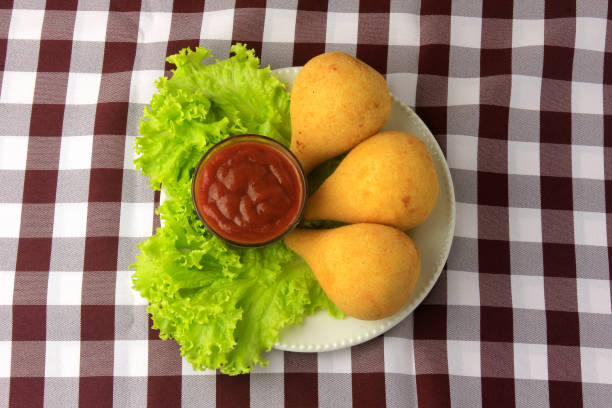 Coxinha in the dish, traditional Brazilian cuisine snacks stuffed with chicken, on rustic wooden table. Top view