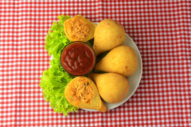 Coxinha in the dish, traditional Brazilian cuisine snacks stuffed with chicken, on rustic wooden table. Top view
