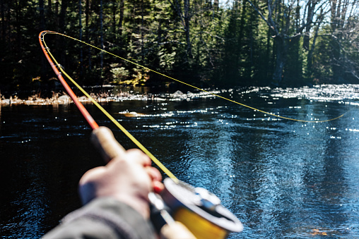 A teenaged male fisherman enjoying a beautiful day out fishing for trout in Nova Scotia