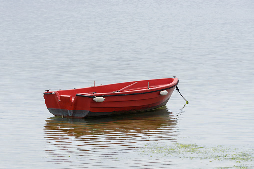 image of red wooden fishing boat moored at the sea
