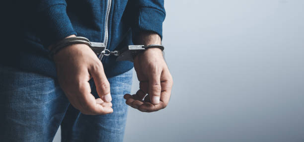 istock young man hand handcuffs on dark background 1140264940