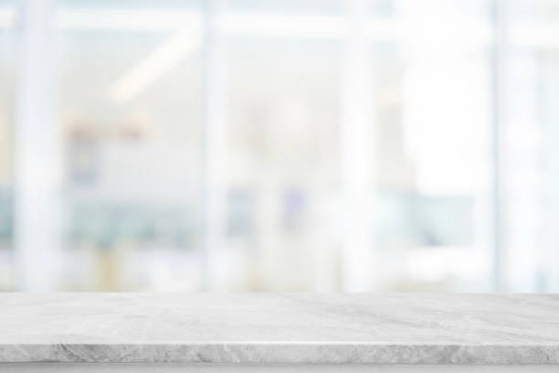 istock Empty white stone marble table top and blurred abstract background from shopping mall background - can used for display or montage your products. 1140269997