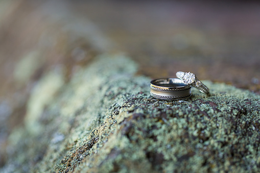 Two diamond wedding rings atop a moss covered rock