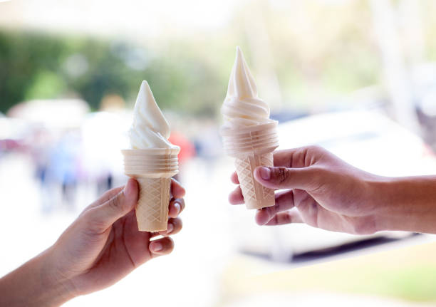 istock hands holding melting ice cream waffle cone in hands on summer light nature background. 1140286356