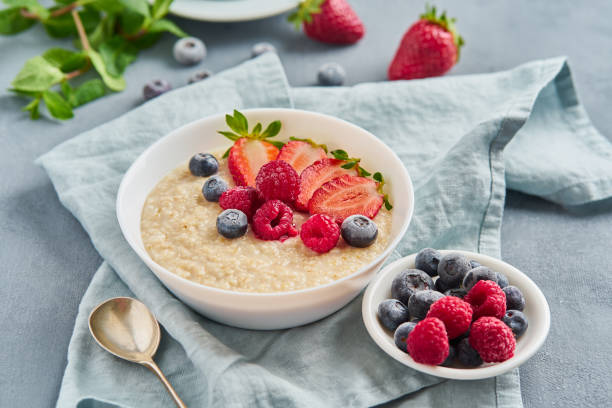 istock Oatmeal with blueberry, strawberry, raspberry on blue dark background. Side view. Healthy diet breakfast 1140286560