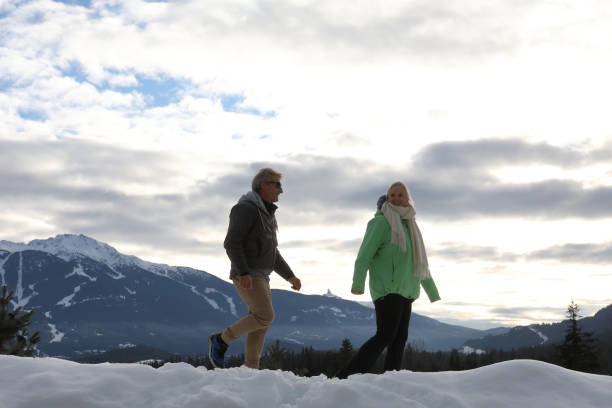 caminhada madura dos pares através da neve profunda - apres ski couple love winter - fotografias e filmes do acervo