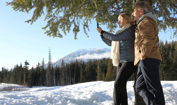 a inclinação madura dos pares de encontro à árvore na neve cobriu o prado - apres ski couple love winter - fotografias e filmes do acervo