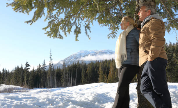 istock Mature couple lean against tree in mountain meadow 1140288841