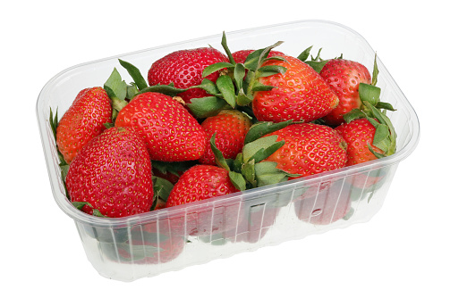 Big strawberry berries in an industrial plastic box. Fruits are grown with the use of nitrates and harmful to health. Isolated on white with patch studio macro
