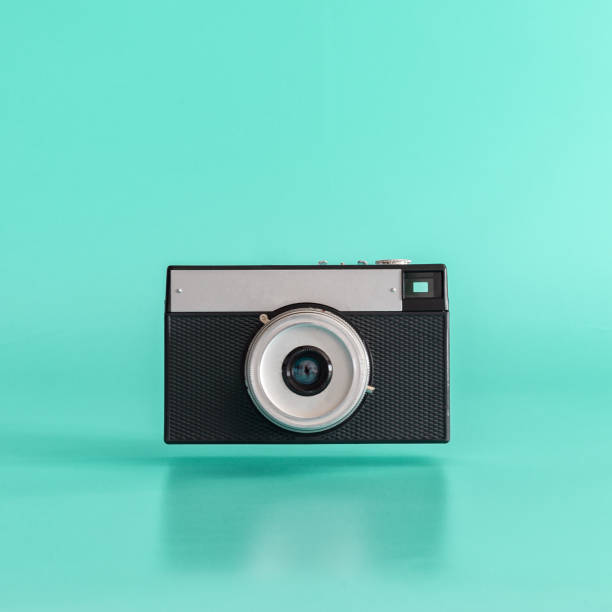 old black film camera levitating on blue background. - ideas concepts aperture black imagens e fotografias de stock