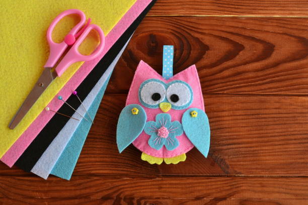 istock Felt owl embellishment. Felt owl toy. How To make a pretty felt owl - kids DIY crafts tutorial. Sheets of colored felt, scissors, wooden table. Step 1140290895
