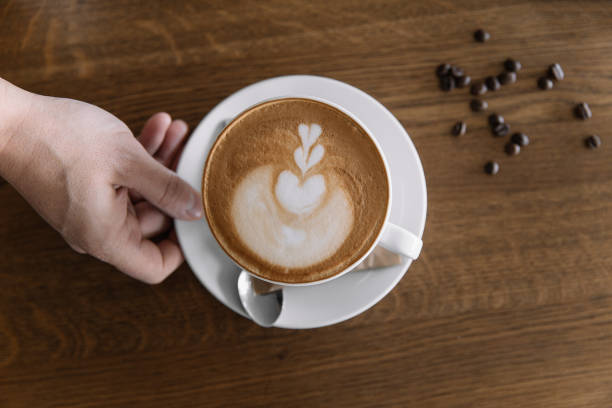 istock Hand holding cappuccino and coffee beans on wooden table 1140291213