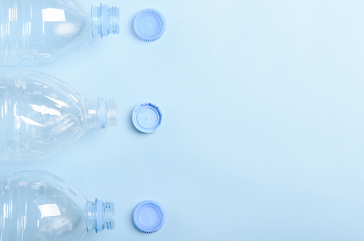 Plastic bottles on a blue background. Concept plastic dishes, clean water, plastic pollution. Copy space, top view, flat lay.