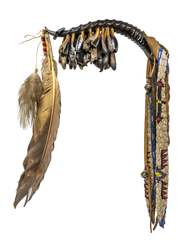 Dance rattle of the North American Indian horn with deer hooves and feathers isolated on white