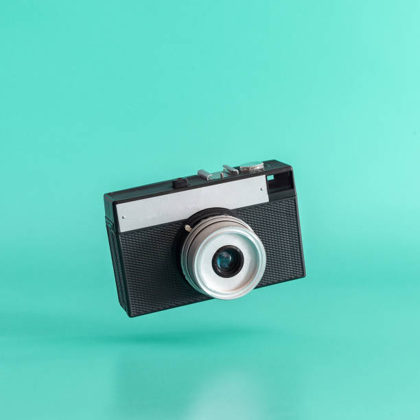 istock Old black film camera levitating on blue background. 1140301633