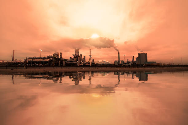 Reflection of refineries and its chimney during the on fire sunset golden hour moment at Rotterdam, Netherlands