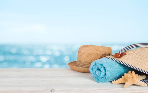 Beach towel, bag and hat on wood over defocused ocean
