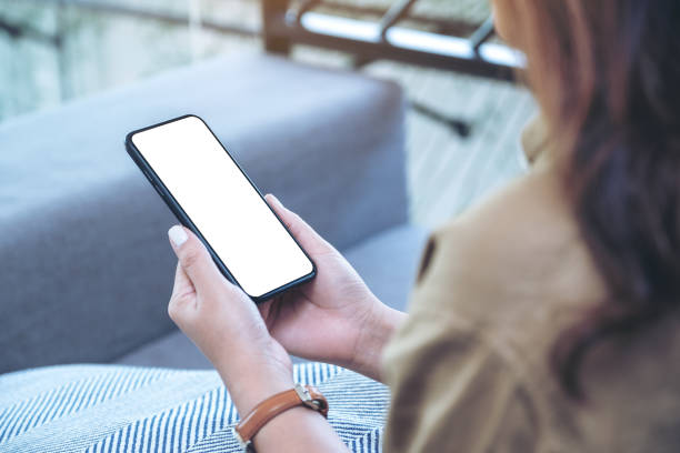 istock a woman holding black mobile phone with blank white desktop screen while sitting in living room 1140303236