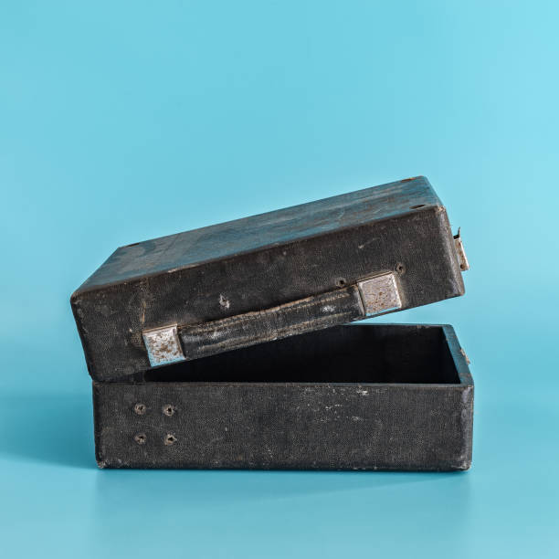 istock Old black shabby open suitcase on blue background. 1140304050