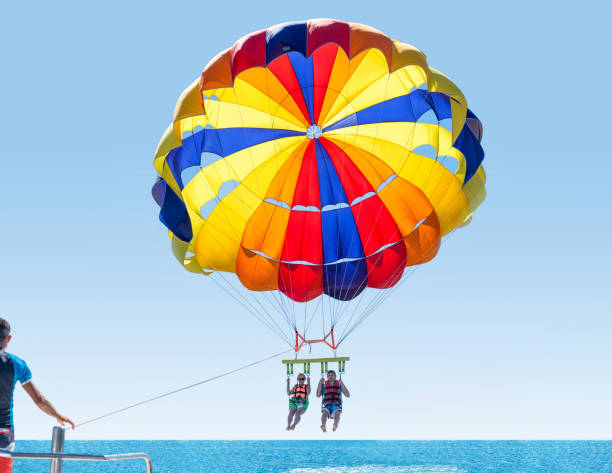 Happy smiling couple Parasailing on Tropical Beach in summer. Newlyweds under parachute hanging mid air. Having fun. Tropical Paradise. Positive human emotions. Happy smiling couple Parasailing on Tropical Beach in summer. Newlyweds under parachute hanging mid air. Having fun. Tropical Paradise. Positive human emotions. parasailing stock pictures, royalty-free photos & images