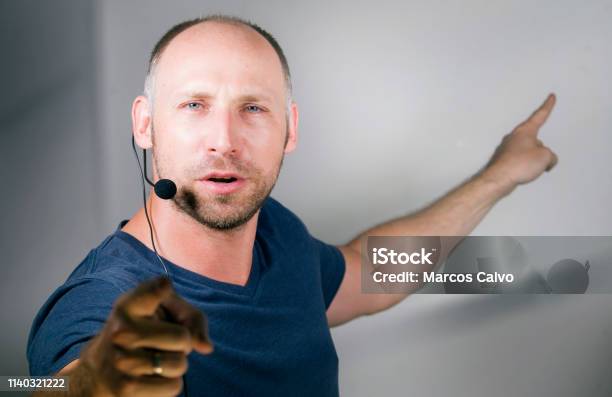 Young Successful And Confident Casual Speaker Man With Headset Speaking At Corporate Business Convention Coaching At Auditorium Conference Room Talking Business Success Training On Speaker Stage Stock Photo - Download Image Now