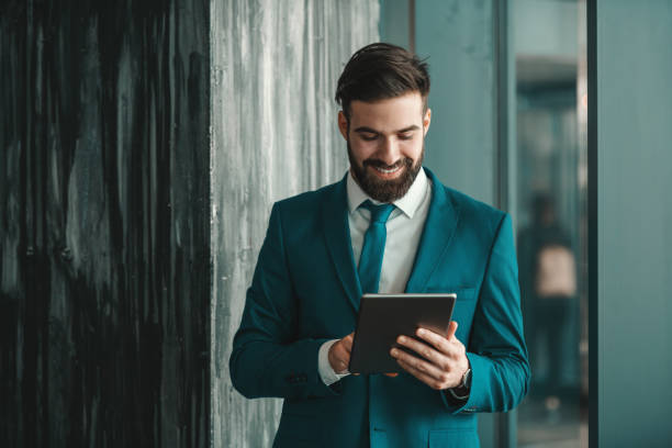 istock Cheerful Caucasian businessman in formal wear using tablet while standing indoors. If it is easy, everyone would do it. 1140326887