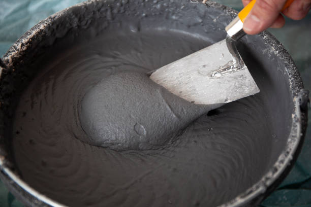 Hand with a Trowel in a Bucket with Plaster Hand of worker with a trowel in a bucket with concrete plaster hand with a plaster spatula stock pictures, royalty-free photos & images