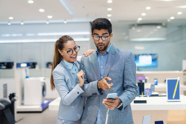 istock Cute multicultural couple dressed elegant choosing new smart phone in tech store. Man pointing at smart phone. 1140330523