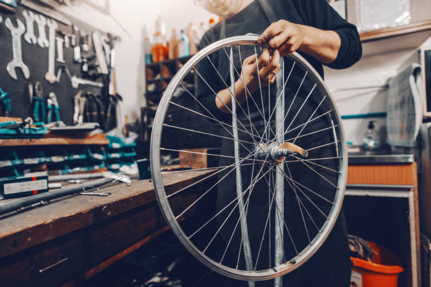 istock Smiling handsome Caucasian man holding bicycle wheel in hands while standing in workshop. 1140336088