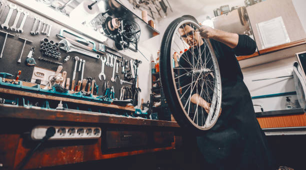 istock Serious handsome Caucasian man holding bicycle wheel in hands while standing in workshop. 1140336206