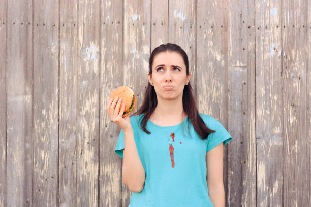 unbeholfene frau staining ihr shirt mit ketchup-sauce - shirt white women blouse stock-fotos und bilder