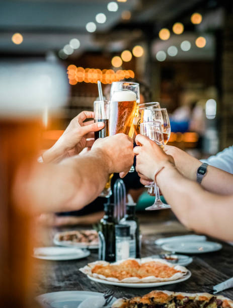 Friends toasting drinks at party in restaurant Friends toasting drinks at party in restaurant. Men and women are celebrating at table. They are enjoying weekend together. beer alcohol stock pictures, royalty-free photos & images