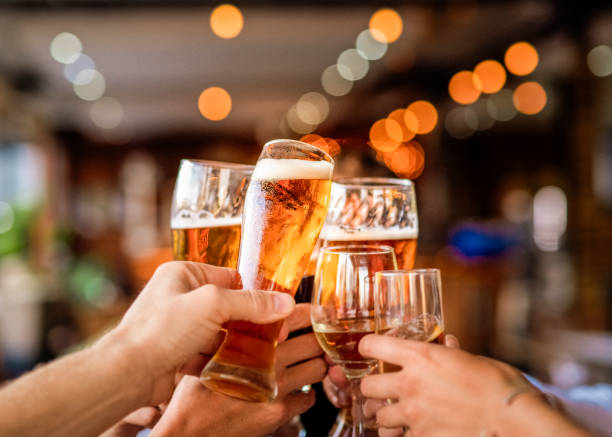Hands of friends raising celebratory toast at bar Hands of man and woman holding drinks at restaurant. Male and female friends are raising celebratory toast. They are enjoying during party. toasting stock pictures, royalty-free photos & images
