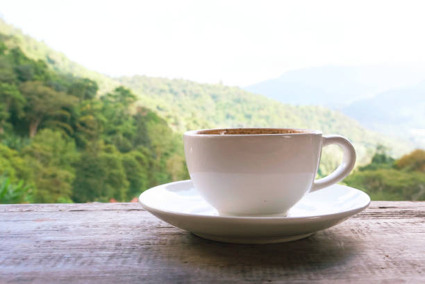 istock White coffee cup on wood table with background landspace mountain 1140339443
