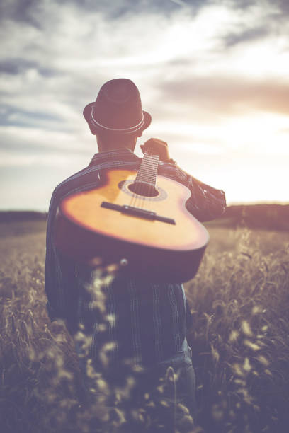 istock Man walking through the wheat field with guitar on back. 1140340803