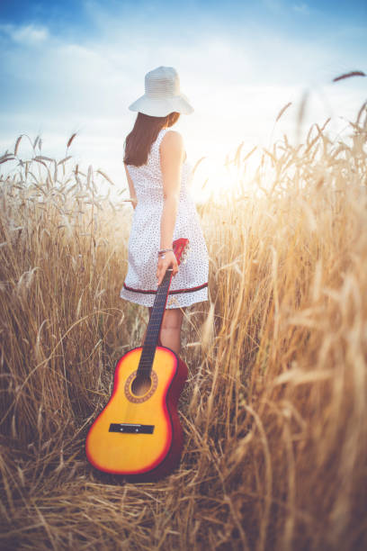 istock Woman with a guitar walking  through a high grass. 1140341210