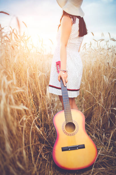 istock Woman with a guitar walking  through a high grass. 1140341252