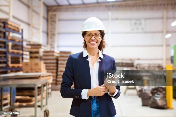 Portrait Of Smiling Businesswoman Wearing Hardhat Stock Photo - Download Image Now - Business, Manufacturing, Visit
